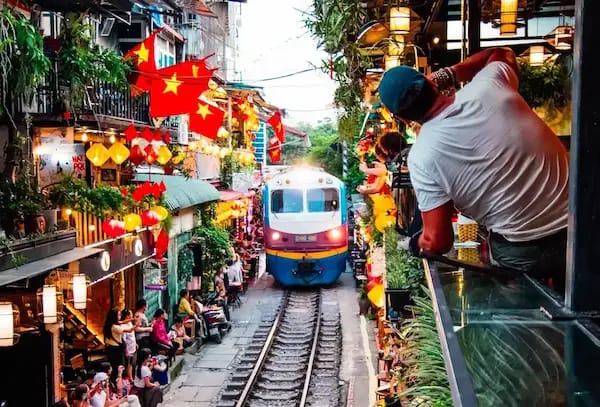 A tourist's taking picture of a coming train in Hanoi's train street